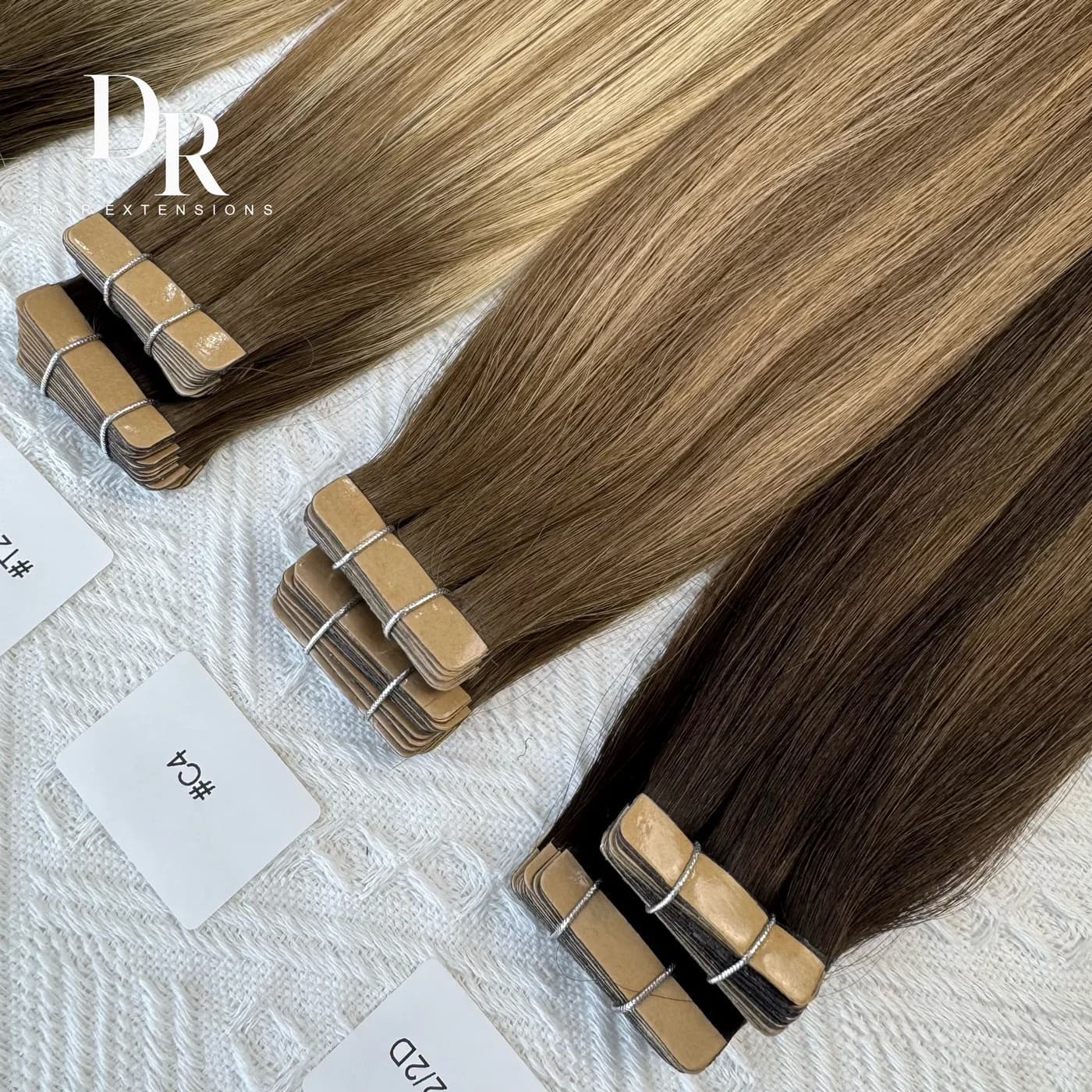 Brown and blonde DR Tape-in bundles arranged with their flat tabs and shade labels visible