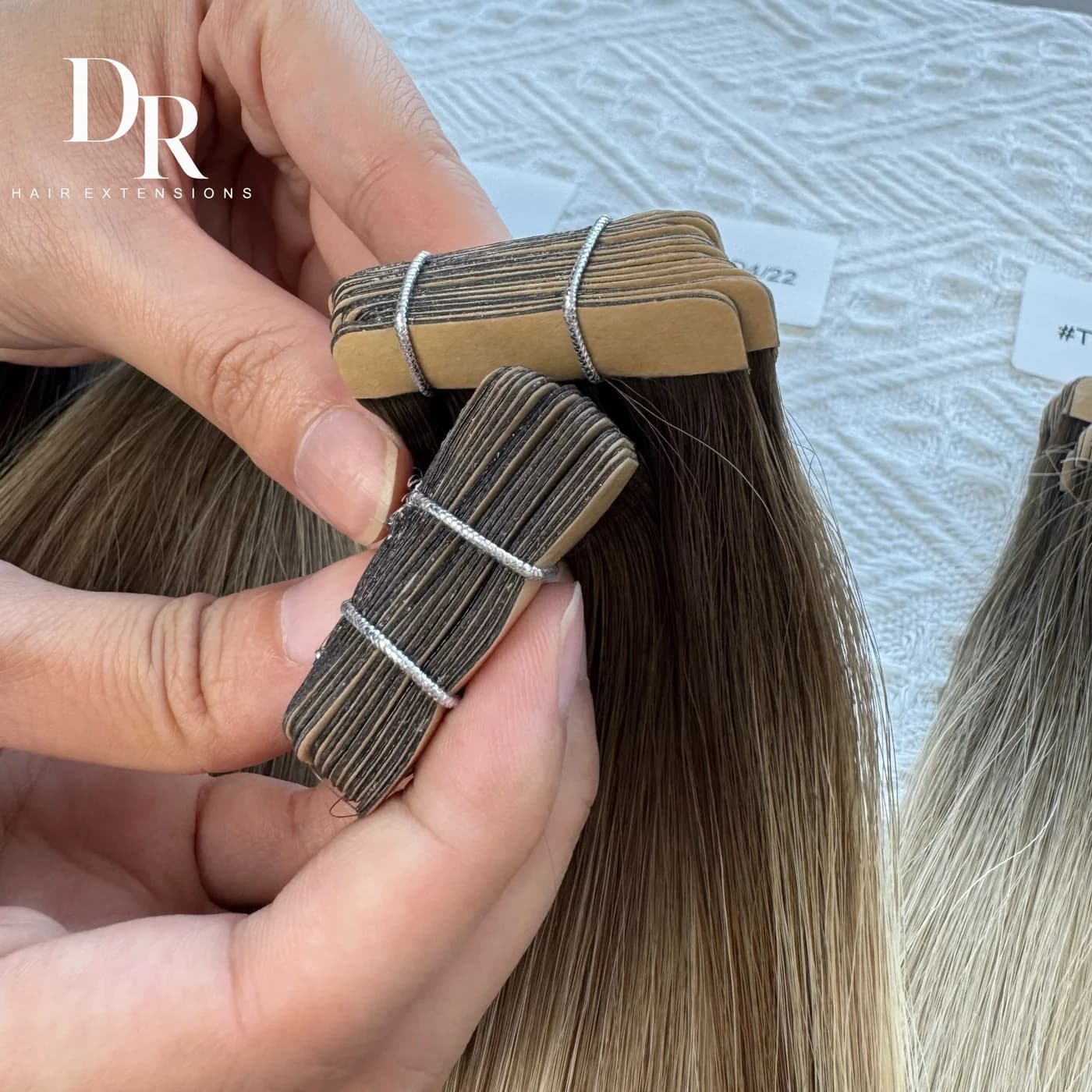 Close-up of DR Tape-in Hair tabs held open to show their flat attachment areas