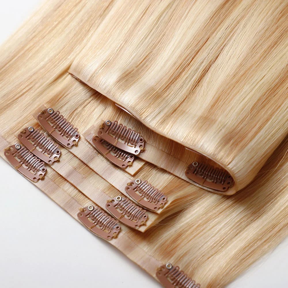 Layered blonde clip-in hair pieces with light bases and brown metal clips visible