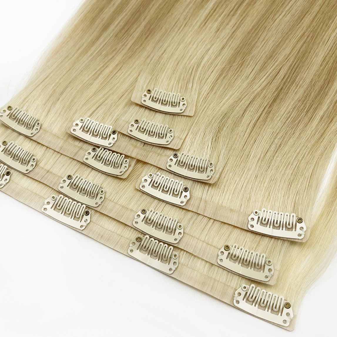 Pale blonde clip-in pieces laid in overlapping rows with light-colored clips visible