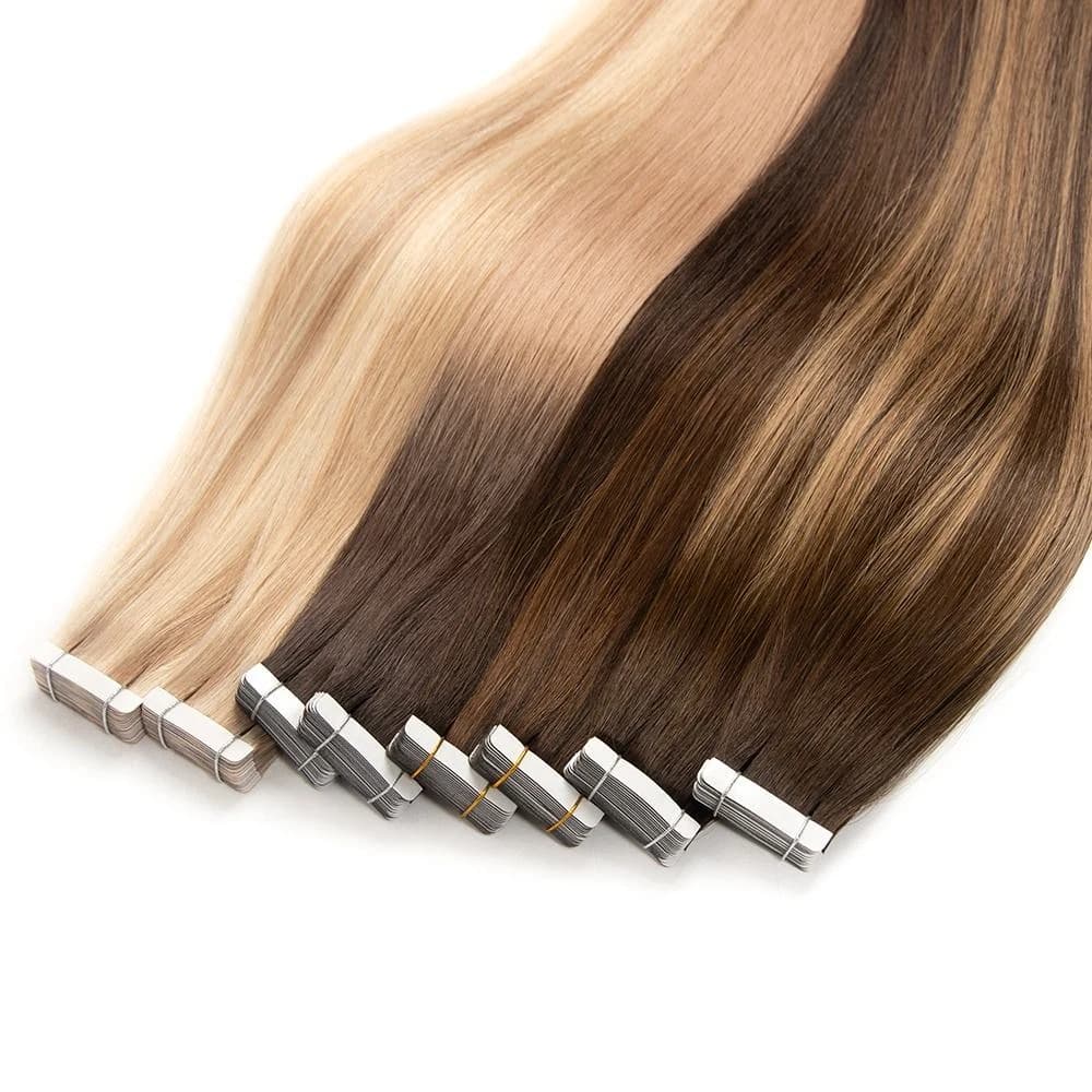 Blonde, brunette and blended tape-in hair bundles with backed tabs arranged on a white surface