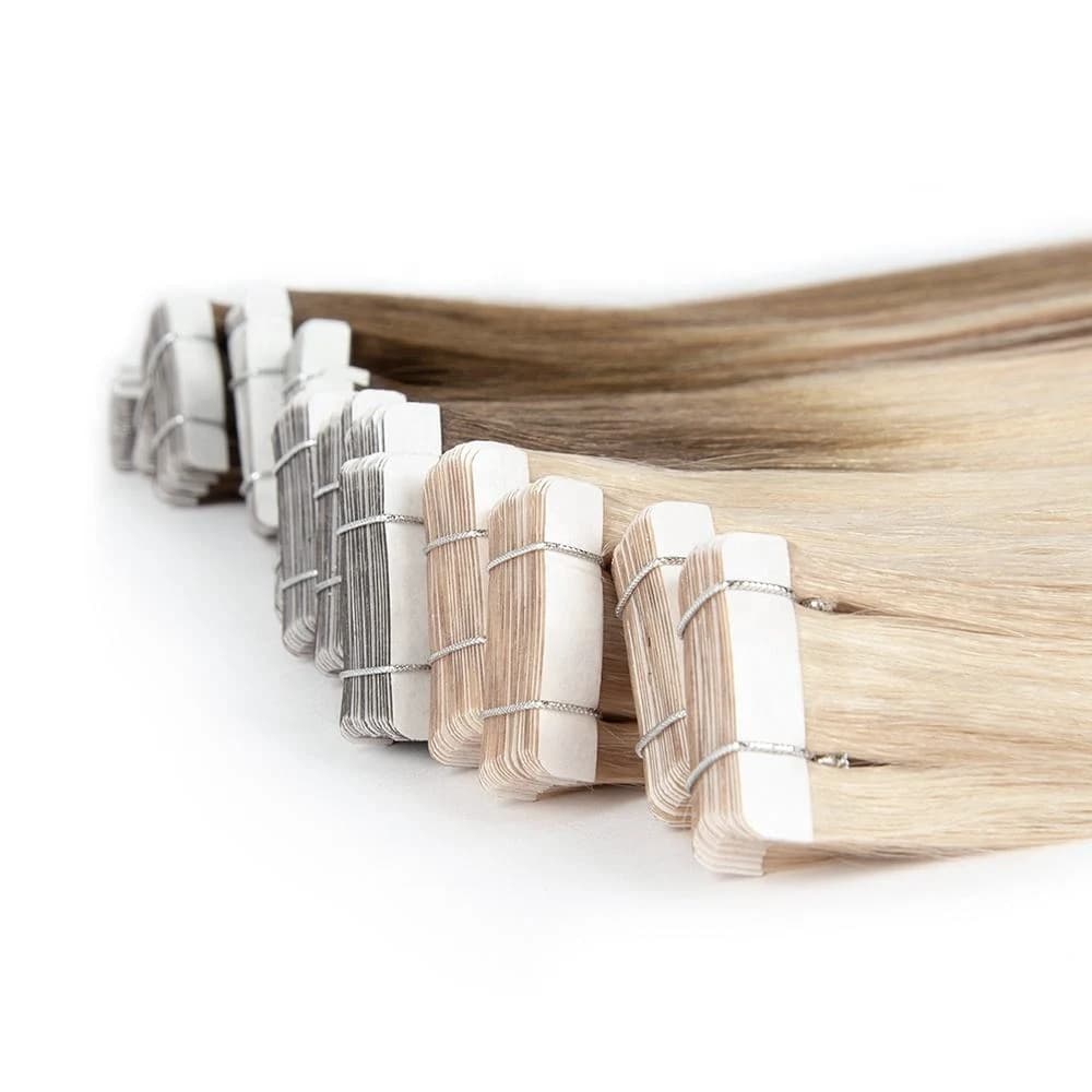Blonde and brunette tape-in bundles lined up with their protective backing visible