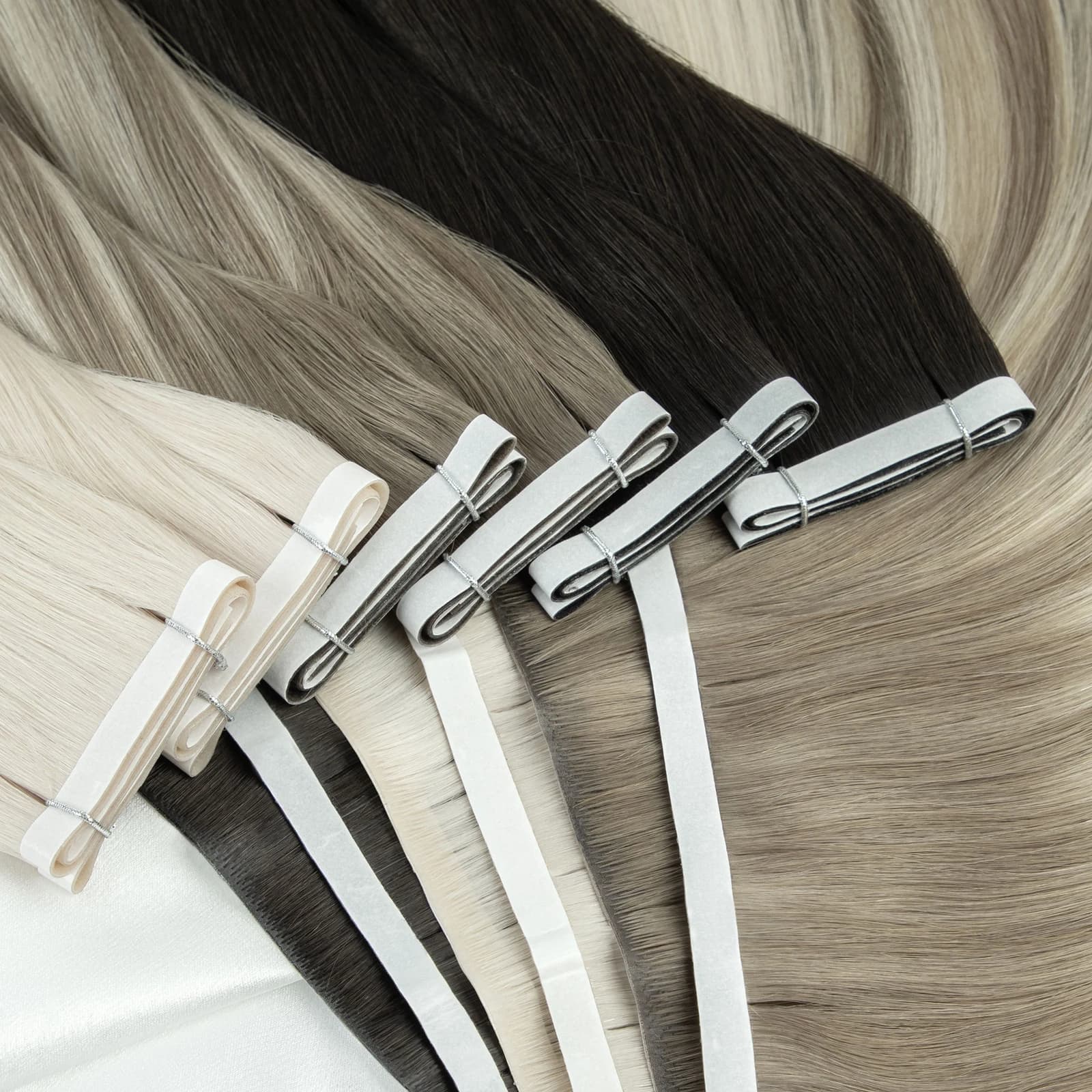 Light and dark hair extension bundles arranged with their folded attachment edges and white protective material visible