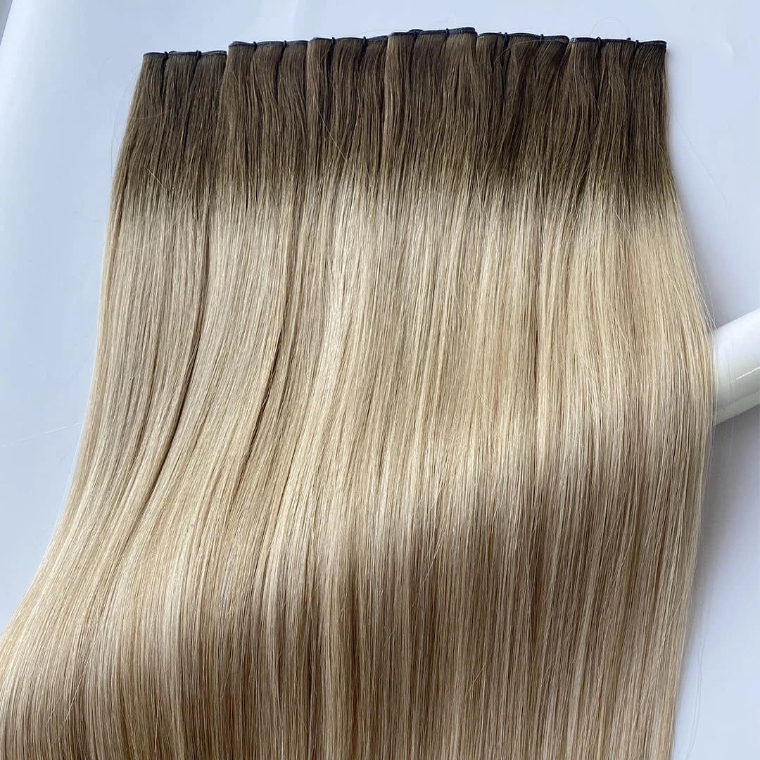 Rooted blonde weft hair arranged side by side with narrow dark attachment edges visible at the top