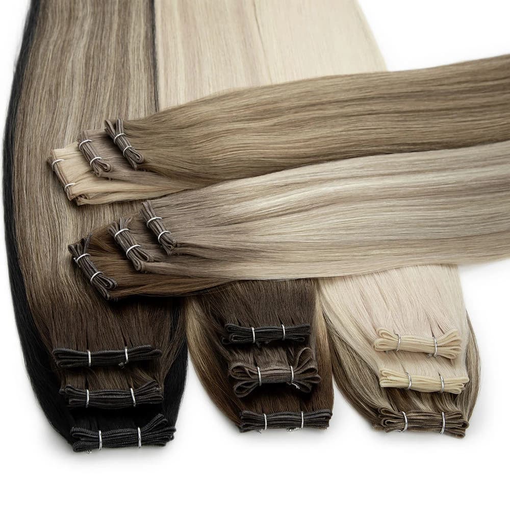Blonde, brunette and blended hair extension weft bundles arranged with folded sewn edges on white