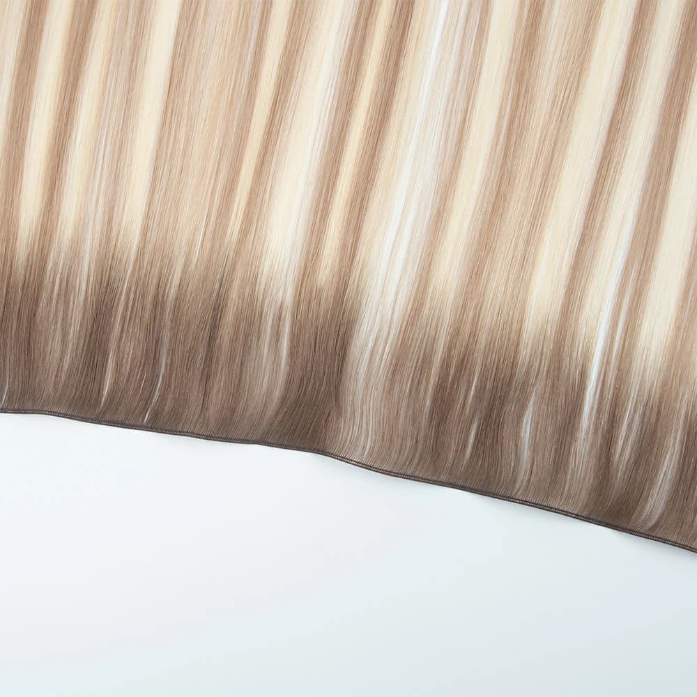 Dimensional blonde hair extension weft with a narrow seam on a light background