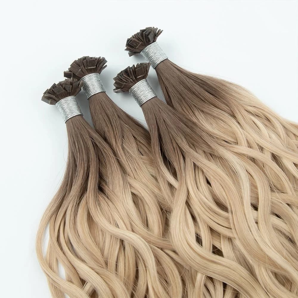 Four bundles of wavy rooted blonde hair extensions with individual tips