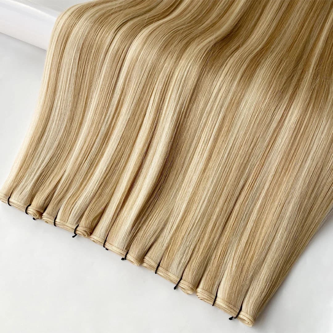 Blonde weft hair extensions displayed side by side with their sewn edges visible