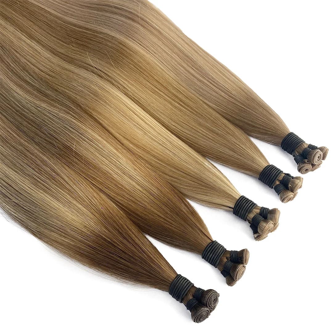Warm brown and bronde weft bundles showing tied ends and rolled sewn seams